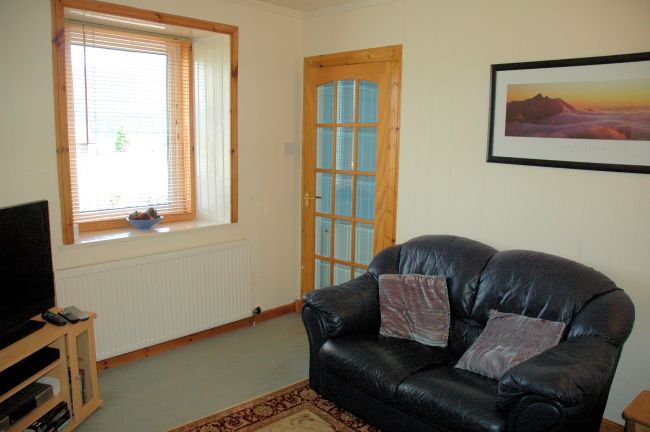 The sitting room in Bruaich Cottage, Lochcarron is cosy with a traditional fireplace and has splendid views.