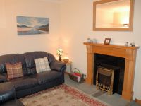 The sitting room in Bruaich Cottage is cosy with a traditional fireplace and has splendid views.